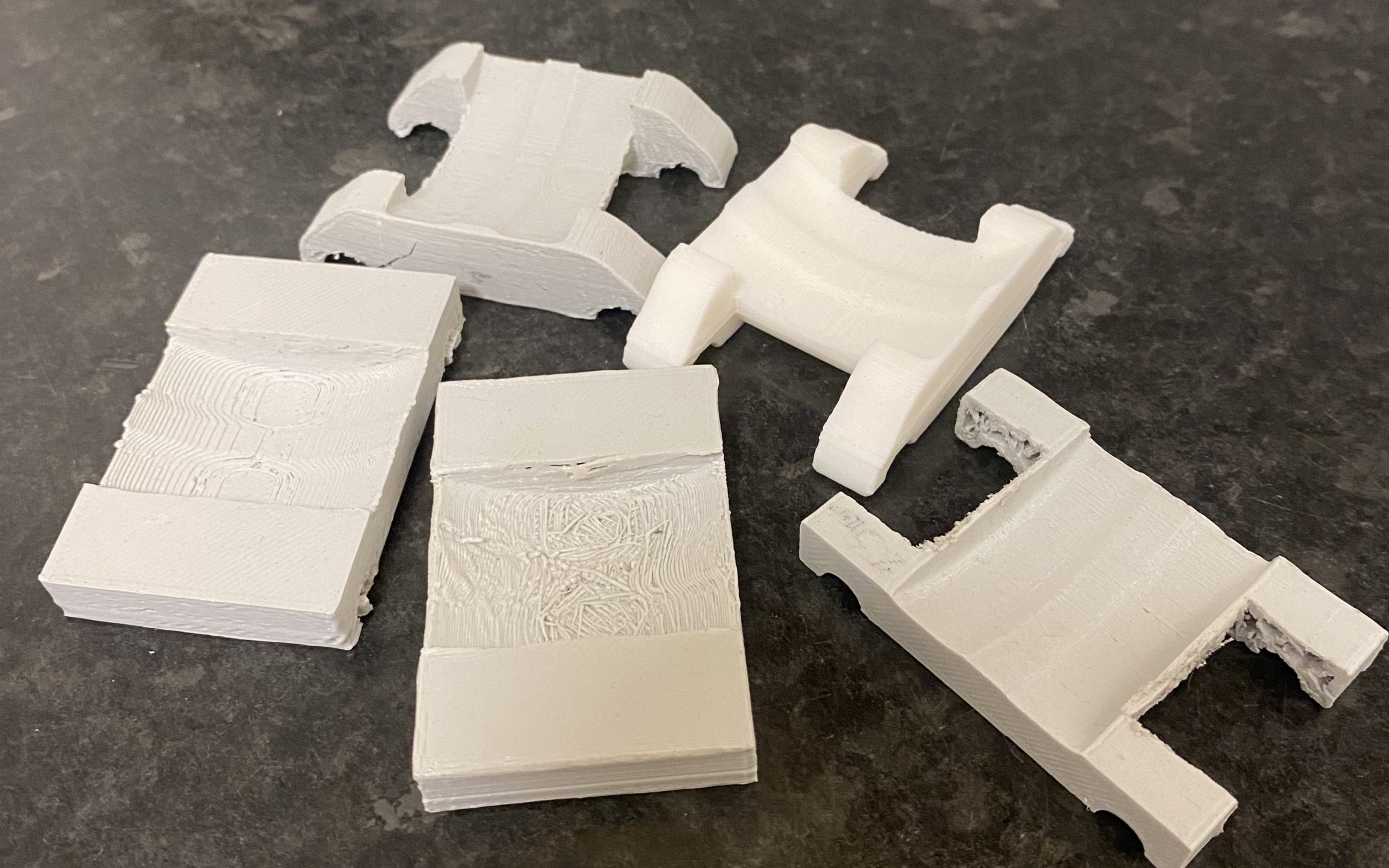 Several prototype 3D prints. Early ones are to check the fit and later ones feature cut-outs for the wing clamps. 