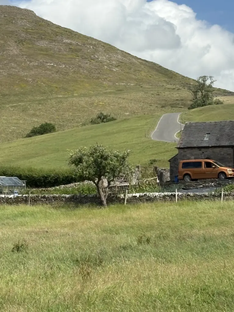 View of stone cottage with strip of steep road in the distance